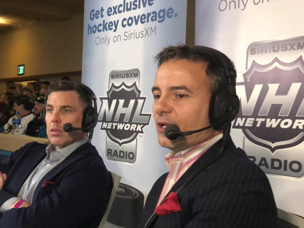 Host talks on radio show in front of NHL Banner